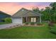 Charming home with a well-manicured lawn, a two-car garage, and beautiful landscaping at sunset at 409 Carousel Ct, Summerville, SC 29483