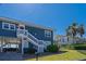 Charming beach house with stairs, a palm tree, and a well-maintained lawn at 412 Palmetto Blvd, Edisto Island, SC 29438