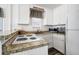 Compact kitchen features white appliances, granite countertops, and a backsplash at 412 Palmetto Blvd, Edisto Island, SC 29438