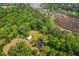 Expansive aerial perspective showcases a property surrounded by dense woodland, complemented by a barn and river at 4942 Storage Rd, Meggett, SC 29449