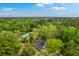 Stunning aerial view of a home and barn nestled among trees in a lush green landscape under a bright blue sky at 4942 Storage Rd, Meggett, SC 29449