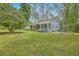 Charming home with a covered porch, rocking chairs, and a well-maintained front yard surrounded by mature trees at 4942 Storage Rd, Meggett, SC 29449