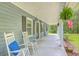 Charming porch with white rocking chairs and hanging ferns offers a relaxing outdoor space with views of the yard at 4942 Storage Rd, Meggett, SC 29449