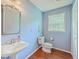 Charming powder room with pedestal sink, decorative mirror, and hardwood floors at 4942 Storage Rd, Meggett, SC 29449