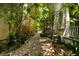 A brick path lined with greenery and trees along the side of a house, providing a charming outdoor space at 62 Society St, Charleston, SC 29401