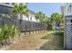 Backyard with a dark horizontal fence, palm trees, green grass and a home exterior that has a white facade at 625 Ocean Blvd, Isle of Palms, SC 29451