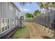 Backyard area featuring a dark fence, palms, a home's exterior with a light gray facade, and a grassy lawn at 625 Ocean Blvd, Isle of Palms, SC 29451