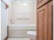 Cozy bathroom with a bathtub and shower combination, toilet, and wooden door with wood trim at 625 Ocean Blvd, Isle of Palms, SC 29451