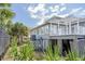 Back exterior featuring a charming deck with a pergola, surrounded by lush tropical landscaping, and a light gray facade at 625 Ocean Blvd, Isle of Palms, SC 29451