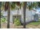 Home exterior featuring a balcony, palms, lush greenery, and a light gray facade at 625 Ocean Blvd, Isle of Palms, SC 29451