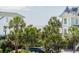 A glimpse of the ocean between beach houses and palm trees on a bright day at 625 Ocean Blvd, Isle of Palms, SC 29451