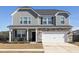 Charming two-story home boasts stone accents, a two-car garage, and a welcoming front porch with seating at 705 Squire Pope Rd, Summerville, SC 29486