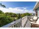 Inviting outdoor balcony offers comfortable seating and views of lush green trees and blue skies at 73 Fairway Dunes Ln, Isle of Palms, SC 29451