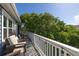 Relaxing balcony features wicker chairs and tranquil view of lush green trees on a sunny day at 73 Fairway Dunes Ln, Isle of Palms, SC 29451