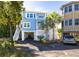 Charming coastal home with a light blue exterior, palm trees, and a covered parking area underneath at 73 Fairway Dunes Ln, Isle of Palms, SC 29451