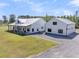 Beautiful farmhouse-style exterior elevation with white siding, metal roof, large covered porch, and detached garage at 733 Oakridge View Trl, Ridgeville, SC 29472