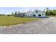 Exterior elevation of a farmhouse-style home with a long driveway, white siding, metal roof, and a detached garage at 733 Oakridge View Trl, Ridgeville, SC 29472