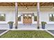 Inviting front porch featuring wooden columns, double doors, modern lighting, and potted plants adding charm at 733 Oakridge View Trl, Ridgeville, SC 29472