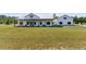 Front view of charming modern farmhouse with a covered porch, white siding, metal roof, and lush green lawn at 733 Oakridge View Trl, Ridgeville, SC 29472
