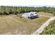 Aerial shot showcasing modern farmhouse with an expansive lawn, white siding, metal roof, and fenced area at 733 Oakridge View Trl, Ridgeville, SC 29472