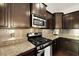 Close up of kitchen stove, microwave, and cabinetry with stainless steel backsplash and granite countertops at 849 Bibury Ct, Charleston, SC 29414