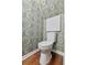 Well-designed half bathroom features modern toilet, designer wallpaper, and hardwood floors at 103 Sylvan Ter, Summerville, SC 29485