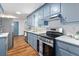 Stylish kitchen equipped with blue cabinets, white countertops, stainless steel appliances, and a view of the dining area at 103 Sylvan Ter, Summerville, SC 29485