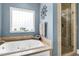 This primary bath has a separate shower and soaking tub with natural light from a window at 1069 Blockade Runner Pkwy, Summerville, SC 29485