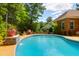 Enjoy this private backyard pool with stone waterfall feature, lush greenery, and cozy poolside lounge area at 1069 Blockade Runner Pkwy, Summerville, SC 29485