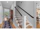 Staircase with oak steps and a black banister offers a glimpse of the entry and living room at 112 Berkshire Dr, Wando, SC 29492