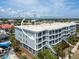 Multi-story condo showcases a corner unit with an ocean view, set amidst lush tropical landscaping on a clear day at 1140 Ocean Blvd # 201, Isle of Palms, SC 29451