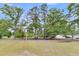 View of the grassy backyard with mature trees, a single Gathering home, and an additional garage at 119 Silver King Ave, Cross, SC 29436