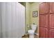 Cozy bathroom featuring a shower with green tile surround, toilet and wood cabinets at 1224 Decoy Ct, Mount Pleasant, SC 29464