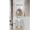 Bright powder room featuring a pedestal sink, oval mirror, updated lighting, wainscoting, and neutral tile flooring at 1224 Decoy Ct, Mount Pleasant, SC 29464