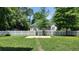 View of the backyard with grass, white fence, and large shady trees at 15 Muirfield Village Ct, Summerville, SC 29483
