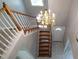 Wooden staircase with chandelier above and bright sunlight shining through a window at 15 Muirfield Village Ct, Summerville, SC 29483