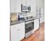 Close up of kitchen appliances including a stainless steel oven, stove top, and microwave with white cabinets at 1634 Pin Oak Cut, Mount Pleasant, SC 29466