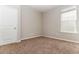 An empty bedroom features neutral walls, plush carpeting, and a bright window with blinds, ready for customization at 1730 Refuge Dr, Ladson, SC 29456