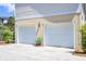 Two car garage with white doors and concrete driveway surrounded by green shrubbery at 1834 Cornish Ave, Charleston, SC 29412