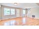 Open-concept living room with hardwood floors, staircase, three windows, and a white entry door at 1834 Cornish Ave, Charleston, SC 29412