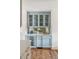 Stylish bar area with pale blue cabinetry, mirrored backsplash, wine cooler, and brass hardware at 19 Ponce De Leon Ave, Charleston, SC 29407