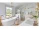 Bright bathroom featuring marble details, tub, chandelier, and glass enclosed shower at 19 Ponce De Leon Ave, Charleston, SC 29407