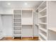 Custom closet with white built-in shelves, brass rods and hardware, and hardwood floors at 19 Ponce De Leon Ave, Charleston, SC 29407