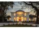 Elegant two-story home with a white brick facade, balcony, and warm interior lighting at twilight at 19 Ponce De Leon Ave, Charleston, SC 29407