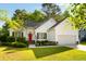 Lovely home with a green lawn, mature trees, and a red door, creating a welcoming curb appeal at 1971 N Smokerise Way, Mount Pleasant, SC 29466