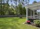 Expansive backyard with lush green grass, mature trees, a cozy firepit, and a screened-in porch at 2016 Elvington Rd, Johns Island, SC 29455