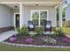 Inviting front porch featuring rocking chairs, a decorative flowerbed, and a black front door at 2016 Elvington Rd, Johns Island, SC 29455