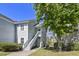Multi-level townhome featuring a stairway to the front door and surrounded by a lush green lawn and mature trees at 2030 Coldspring Dr # 708, North Charleston, SC 29406