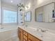 Bright bathroom with double sinks, wood cabinets, a soaking tub under a bright window, and neutral walls at 219 Silverwood Ln, Summerville, SC 29485