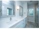 Bright bathroom featuring dual sinks, framed mirrors, and a glass-enclosed shower at 2501 Myrtle St, Edisto Beach, SC 29438